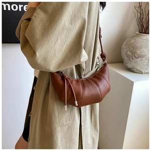 Detail of caramel brown crescent bag with lychee grain leather and knotted strap