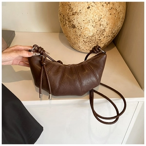 Detail of dark brown croissant bag with pleated seams and slim shoulder strap