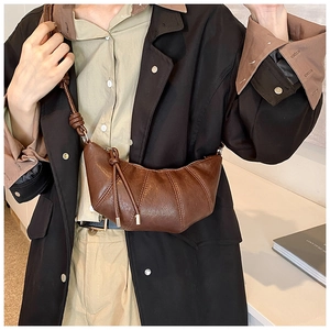 Detailed view of brown croissant shoulder bag with pleats and knotted leather strap