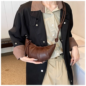 Detailed view of dark brown croissant bag showing pebbled leather texture and layered pleats
