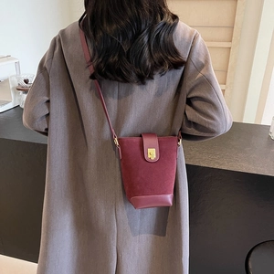 Retro burgundy bucket bag in matte suede and smooth leather shown on model's shoulder