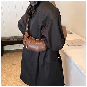 Detail of dark brown croissant bag with segmented stitching and smooth leather texture