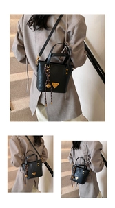 Close-up of black leather bucket bag featuring a golden triangle logo and braided pendant