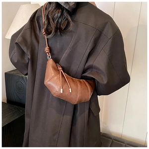 Close-up of a dark brown croissant bag featuring a textured leather finish and stitching