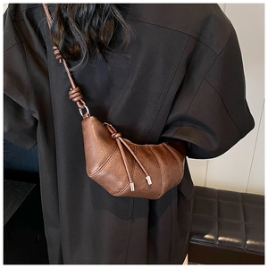 Detailed back view of a brown leather croissant bag with knotted strap on a model