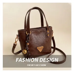 Detail view of coffee brown tote bag with textured synthetic leather and metal accents