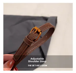 Macro detail of brown leather adjustable shoulder strap with bronze metal buckle clasp