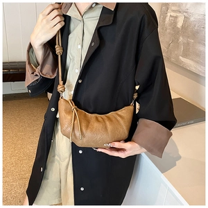 Detail of a brown vintage pleated croissant bag with smooth faux leather texture and strap