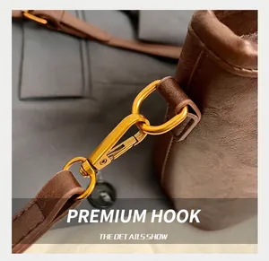 Detail of gold metal hook and textured brown leather strap on a large tote bag