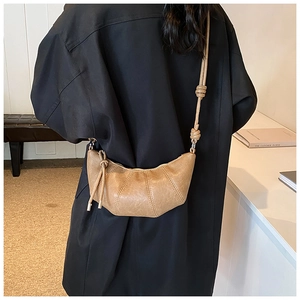 Close-up of retro brown croissant bag with detailed pleats and decorative knot strap