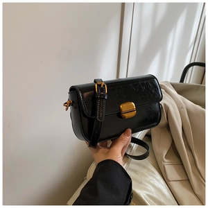 Detail of vintage black patent leather crossbody bag with golden metal buckle clasp