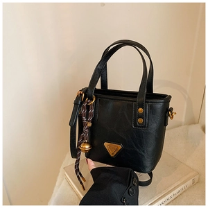 Detail of black tote bag with vintage triangle logo and woven bell charm accessory