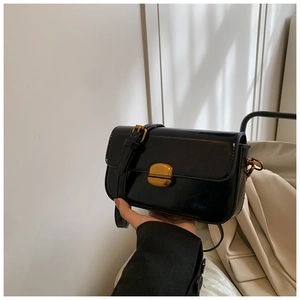 Detailed macro of vintage black leather square bag with a golden oval twist lock clasp