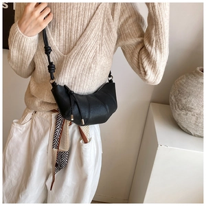 Detail of black leather croissant bag with pleated design and knotted shoulder strap