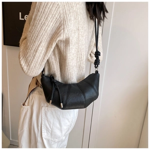 Detail view of black croissant bag featuring shoulder strap knot and soft leather texture