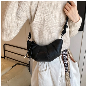 Detail of black crescent croissant bag with sectional stitching and long tassels