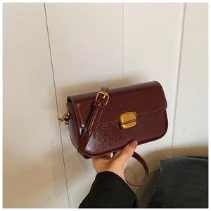 Close-up of vintage burgundy shoulder bag featuring wax leather texture and gold metal buckle