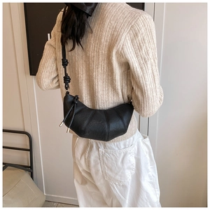 Detail shot of the pleated croissant bag structure and leather shoulder strap on a model