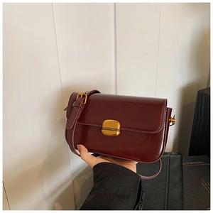Close-up of a vintage dark red leather crossbody bag with a golden rectangular clasp