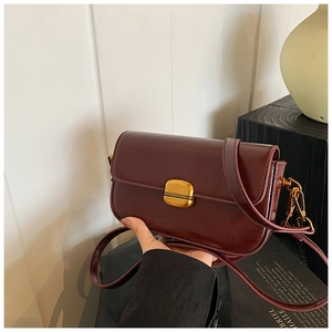Detailed close-up of dark red vintage crossbody bag with a textured gold square buckle