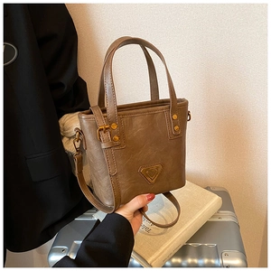 Detail of vintage brown textured crossbody bag with metal triangle plaque and handles
