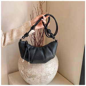 Detailed close-up of a black crescent crossbody bag with knotted strap and pebbled texture
