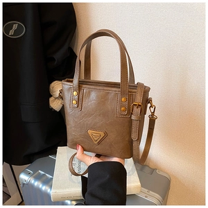 Close-up of brown vintage bucket bag featuring textured faux leather and a metal logo