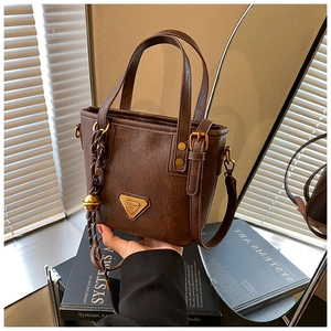Close-up of dark brown vintage PU leather tote with metal logo and spherical charm