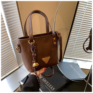 Detail of vintage brown bucket bag with gold hardware and woven bell charm accessory