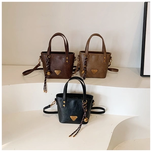 Close-up of texture and metal accents on three leather-style bucket bags in various colors