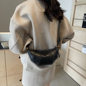 Sac bandoulière noir forme croissant avec détail de nœud porté par un mannequin