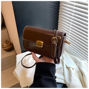 Close-up of vintage brown leather crossbody bag with golden buckle and oil wax finish