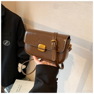 Close-up of brown vintage crossbody bag with polished synthetic leather and gold hardware