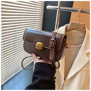 Detailed close-up of dark brown vintage leather bag with a golden metal twist lock