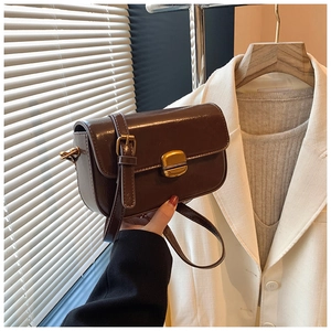 Detail of vintage dark brown faux leather crossbody bag with a gold rectangular metal clasp