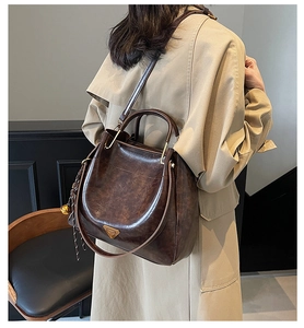 Detail view of a vintage dark brown leather tote bag worn with a beige trench coat