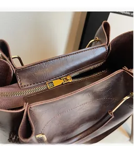 Detailed macro view of the smooth gold metal zipper on a dark brown leather tote bag