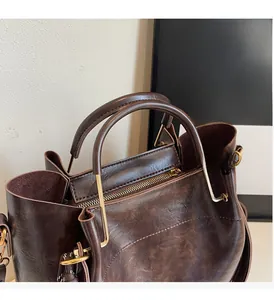 Detail view of dark brown vintage tote bag featuring a semi-circular gold metal handle
