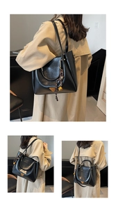 Detail of black faux leather tote bag with metal emblem and woven charm on beige coat
