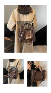 Detail view of brown vintage tote bag featuring a gold bell charm and triangular logo
