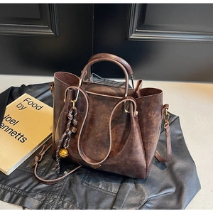 Detail of vintage dark brown faux leather tote with braided charm on a dark aesthetic background