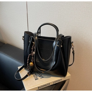 Detail of black leather tote bag with brown woven cord and golden metallic beads