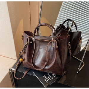 Detail of vintage coffee brown leather tote with golden hardware and woven charm