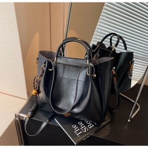 Macro view of black pebbled leather tote bag with gold metal hardware and side knot detail