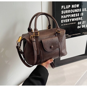 Close-up of retro dark brown textured leather Boston bag with matte gold hardware details