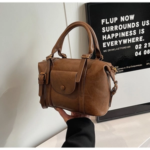 Detail of vintage brown leather handbag with pleated texture and metal buckle pocket