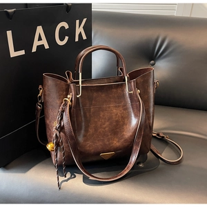 Detailed shot of retro dark brown leather tote bag with metal triangle plaque and charm