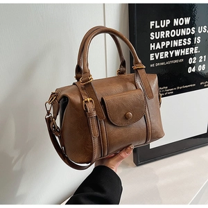 Close-up of vintage brown leather bag featuring lychee texture and bronze hardware buckles