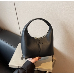 Detail of a black hobo bag with a circular handle and gold double zipper closure