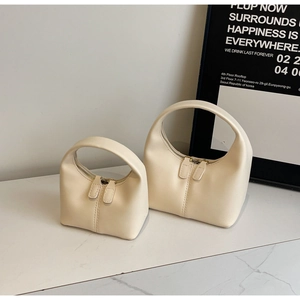 Close-up of minimalist cream leather handbags in two sizes with sleek metal zippers